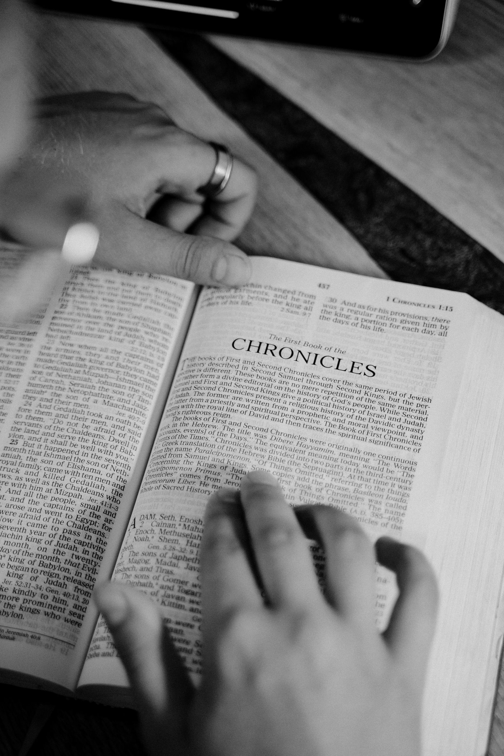 Black-and-white photo of hands reading the Chronicles chapter from a Bible.